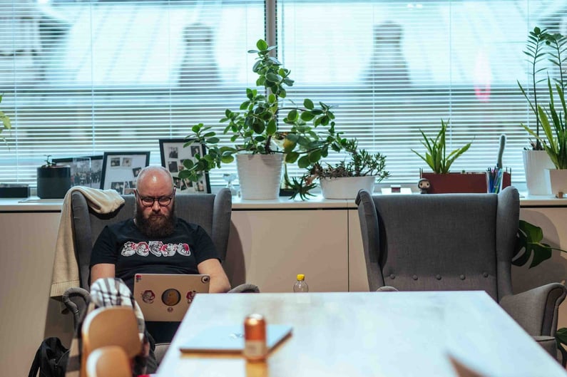 Designer Lauri istuu nojatuolilla kone sylissä ja työskentelee keskittyneesti.