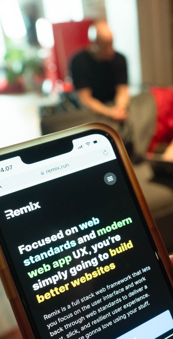 Remixin verkkosivut mobiilissa ja taustalla kehittäjä istuu sohvalla